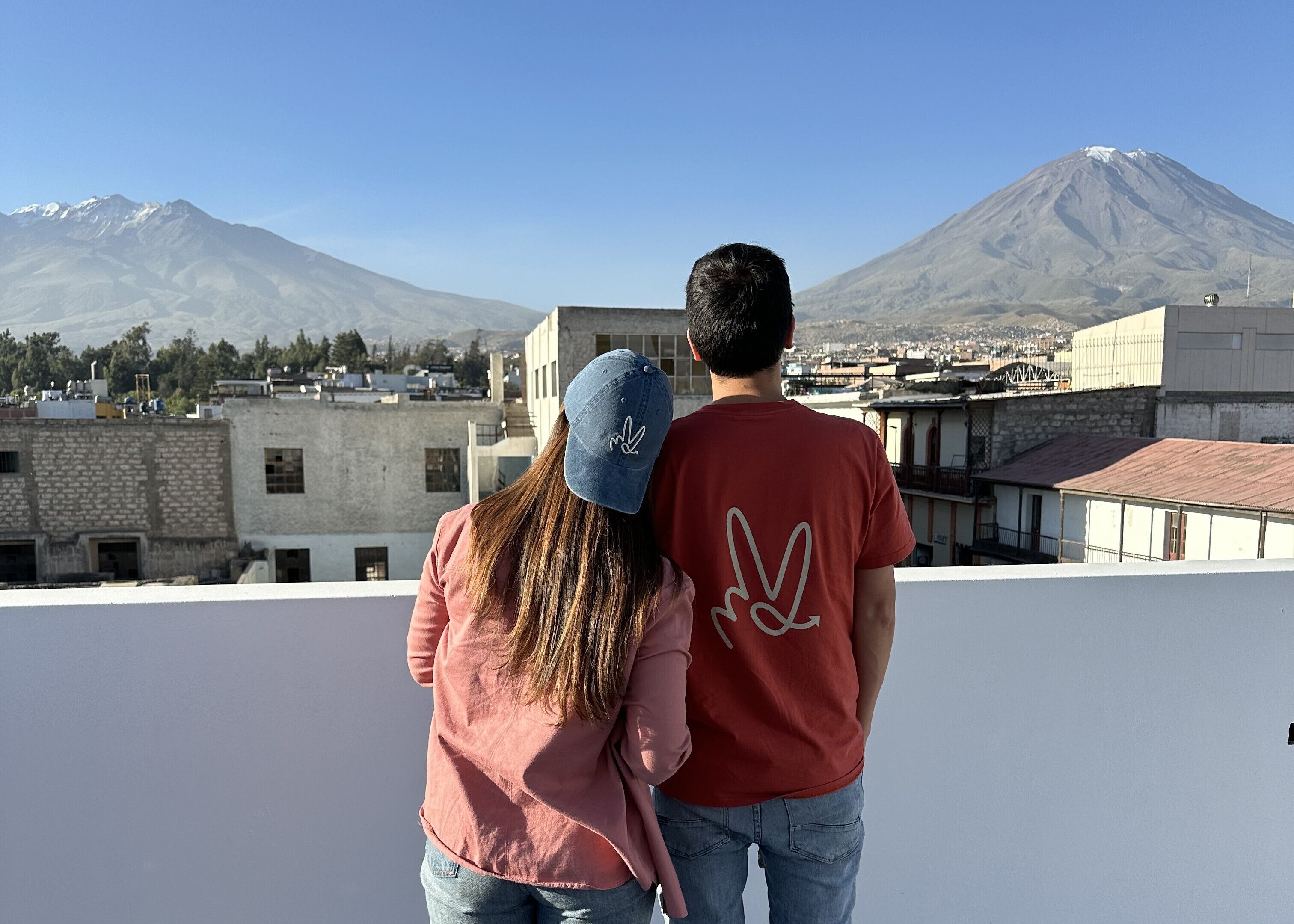 A couple standing on a rooftop with a view of a mountain and buildings in the background.