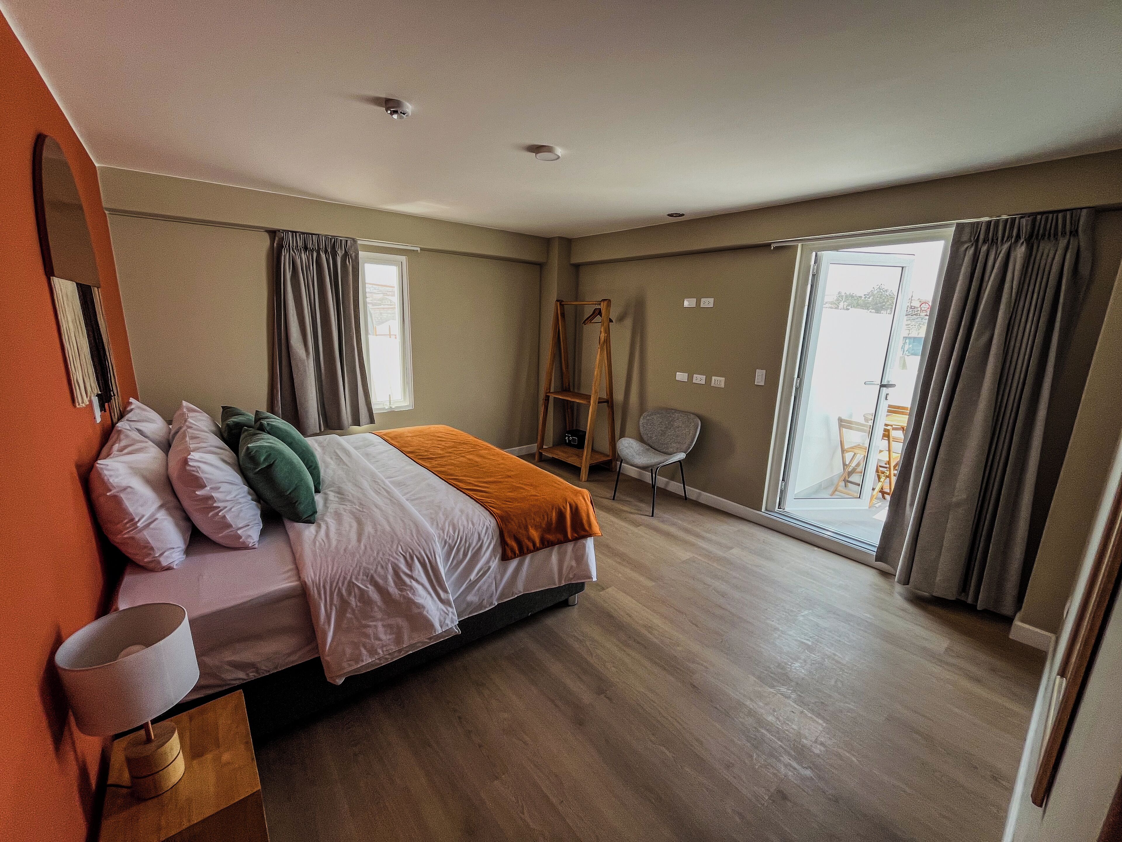 Un dormitorio con cama, una silla, una escalera de madera y un ventanal grande.