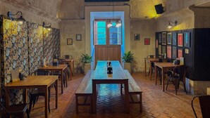 Un interior de restaurante con una larga mesa de madera, varios arreglos de asientos y un letrero que dice 