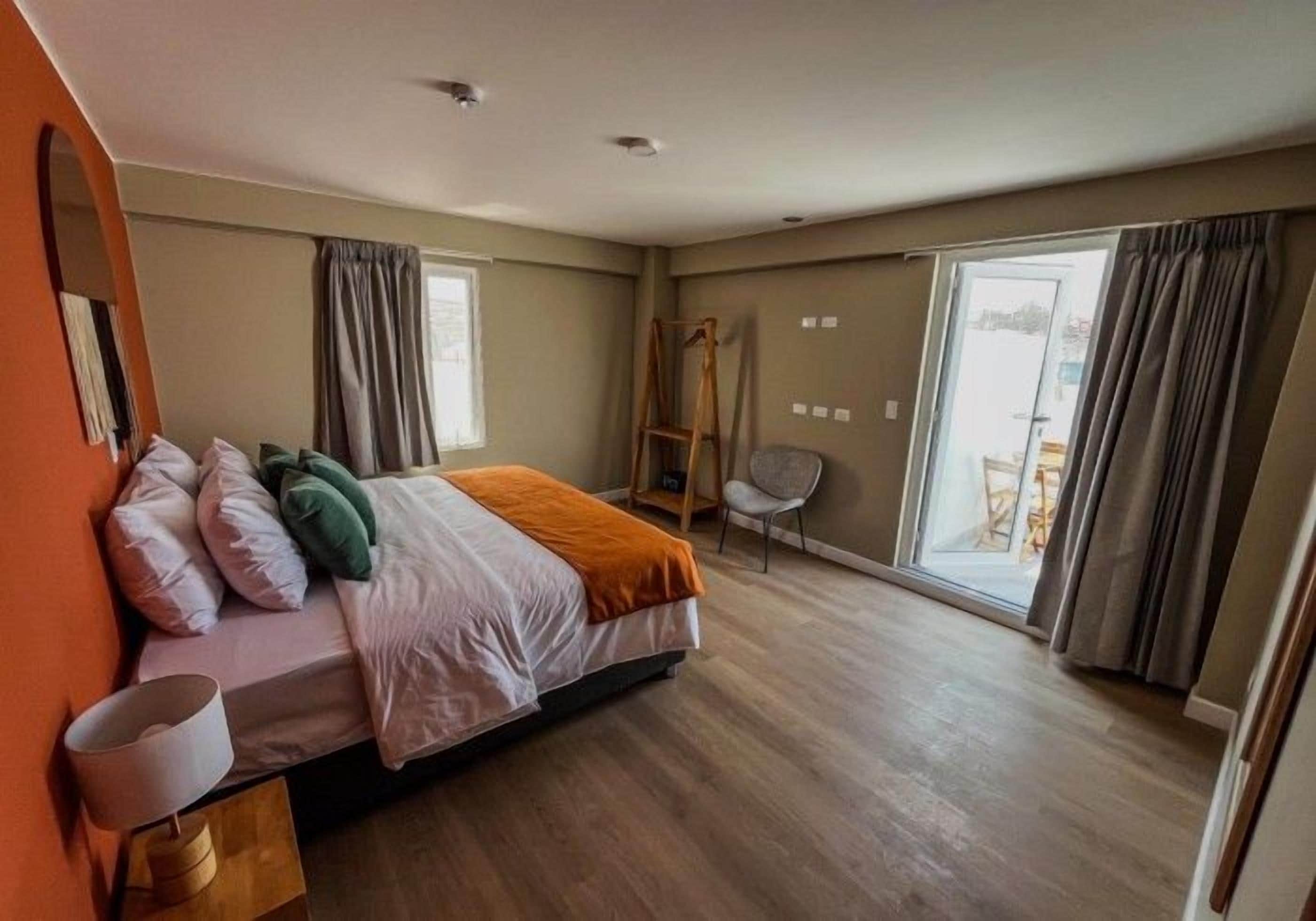 Un dormitorio con cama, una silla, una ventana y una puerta.