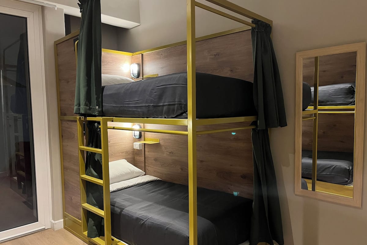 A bunk bed room with a wooden headboard, a small bedside table, and a mirror on the wall.