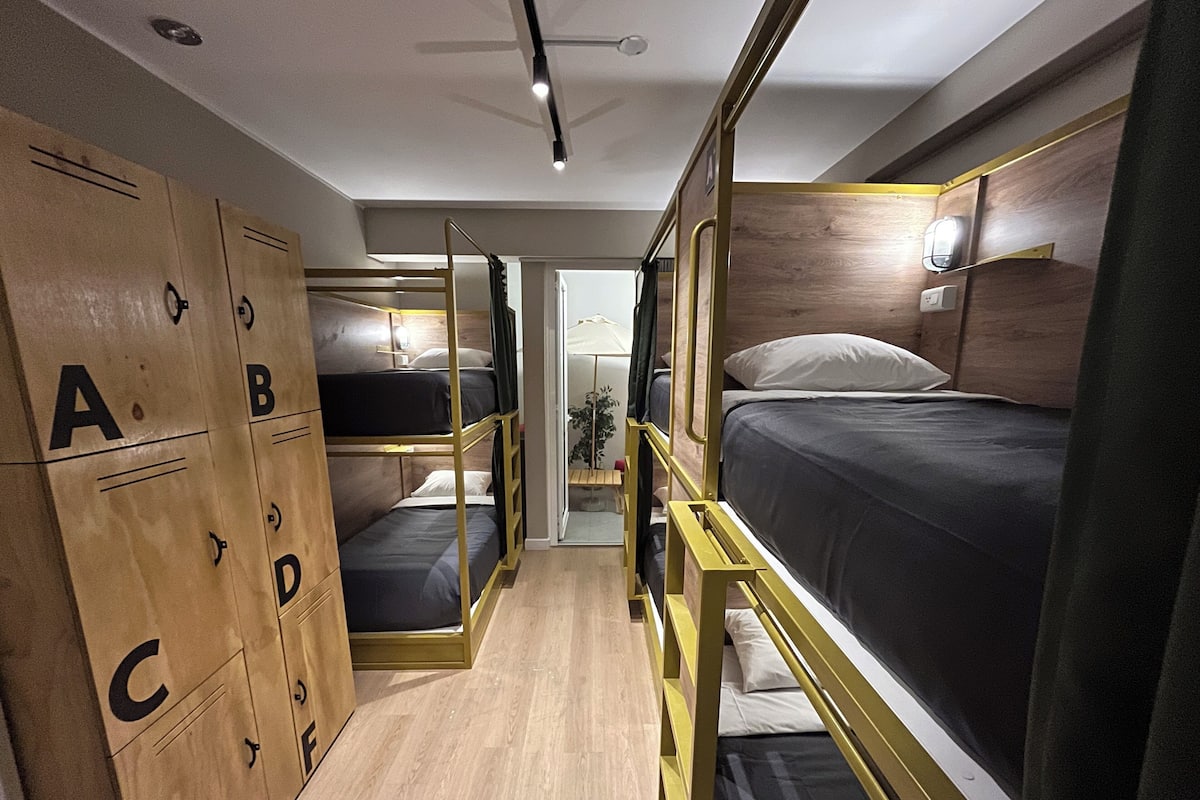 A compact, modern room with bunk beds and a wardrobe with alphabet labels.