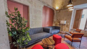Una sala de estar acogedora con un sofá gris, otomanas rojas, una mesa de centro de madera y una planta en maceta.