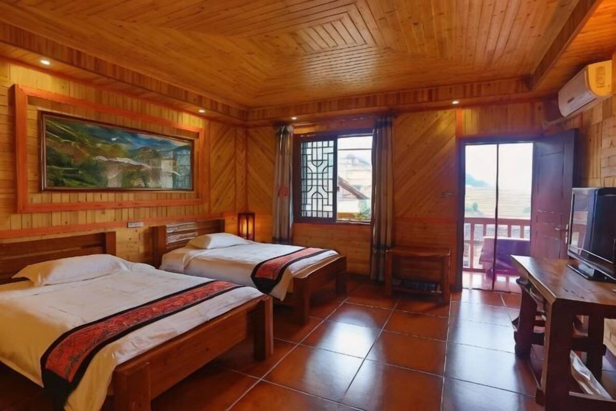 Une pièce en bois avec deux lits, un tableau, une télévision et un balcon.