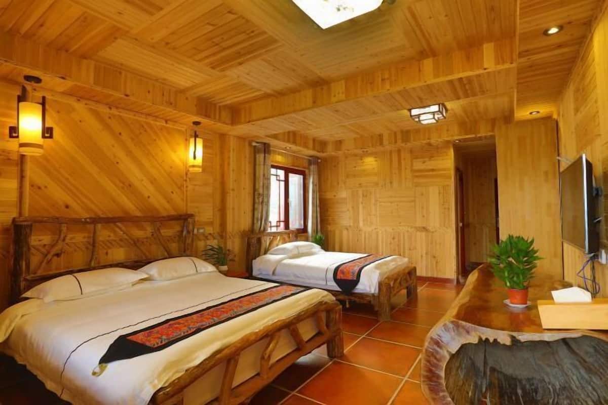 Une pièce aménagée comme un chalet en bois, avec deux lits, une grande table en bois et un téléviseur.