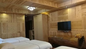 Une pièce en bois avec deux lits, un téléviseur et un banc en tronc d’arbre.