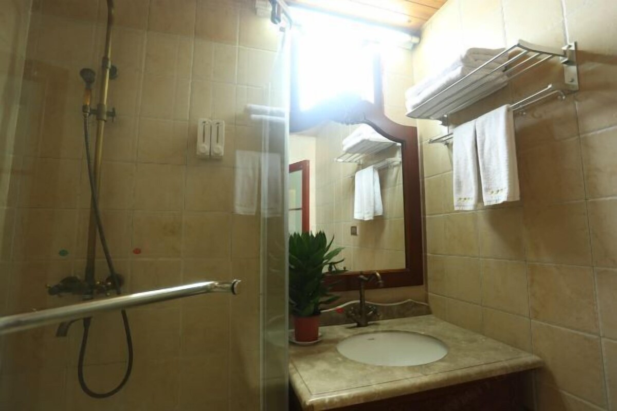 A bathroom with a shower, a sink, a mirror, and a towel rack.