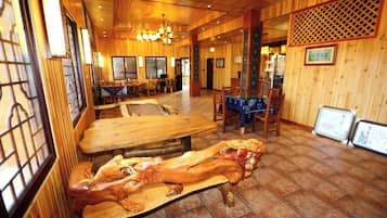 A wooden interior with tables and chairs, a wooden bench, and a patterned wall.