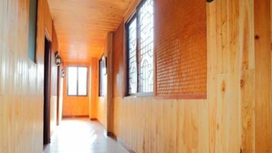 Un couloir en bois, doté de grandes fenêtres et d’un sol carrelé.