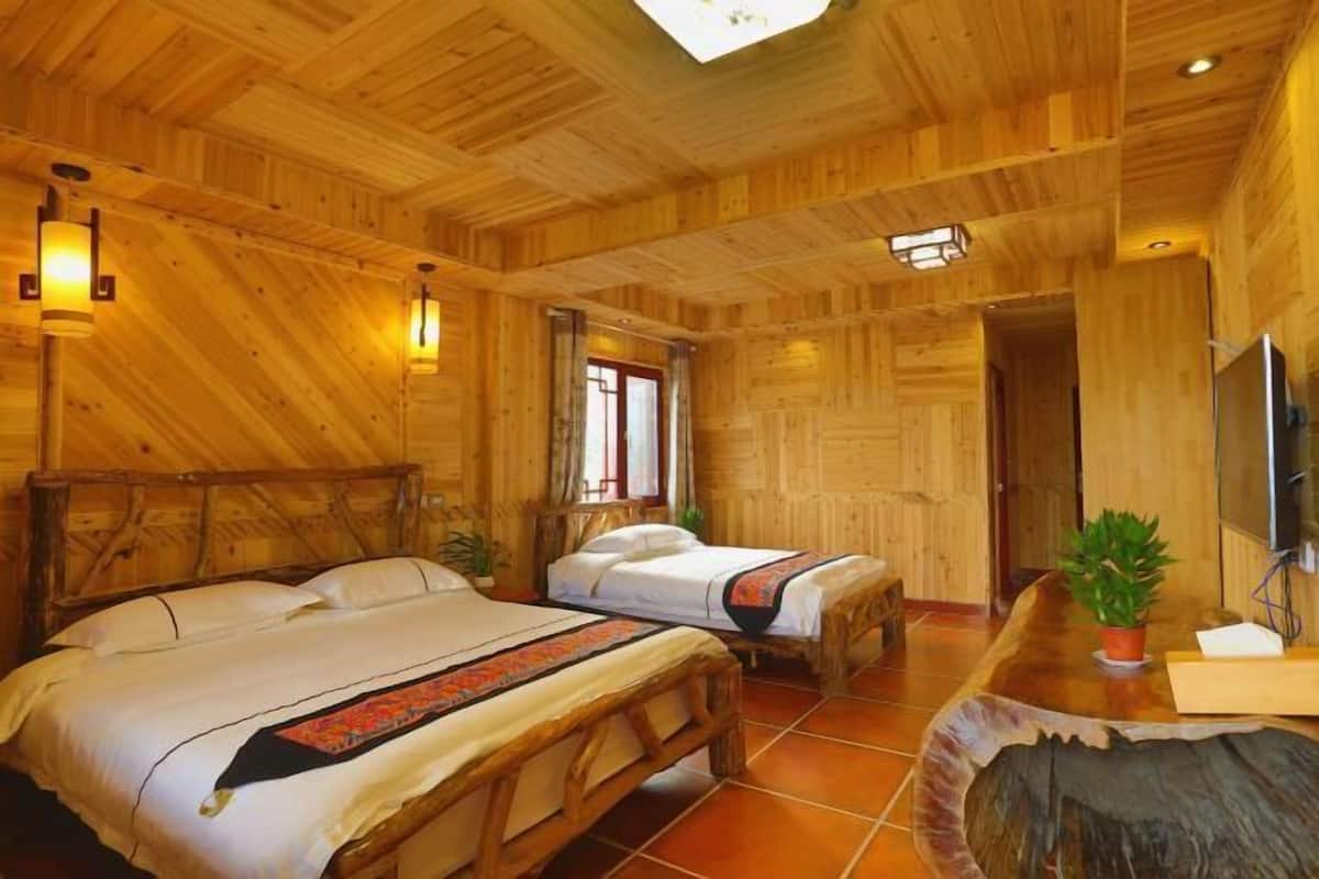 Une cabane en bois avec deux lits, un plafond en bois et une grande fenêtre.
