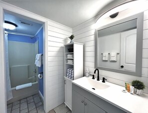 Un baño con ducha, inodoro, lavabo y espejo.