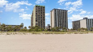 A beachfront hotel with multiple high-rise buildings, a sandy beach, and palm trees. - Stylish Escape Oceanview Suite @ Meridian Plaza! (Myrtle Beach)