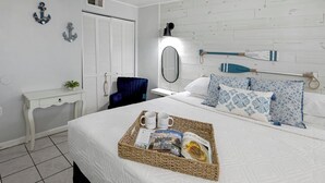 A bedroom with a bed, bedside table, chair, and a wall-mounted mirror. - Stylish Escape Oceanview Suite @ Meridian Plaza! (Myrtle Beach)