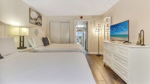 Une chambre d’hôtel avec deux lits, une télévision, une commode et un tableau au mur.