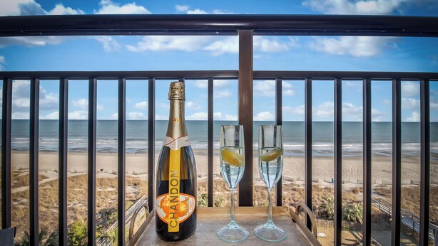 Une bouteille de champagne Chandon et deux verres sur un plateau, avec une vue sur la plage.