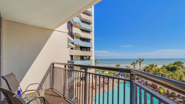 A balcony with a view of a pool and beach. - Luxurious Haven, Oceanview Suite (Myrtle Beach)