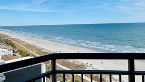 A beach view from a balcony with a railing, sandy beach, and ocean. - Astonishing Oceanview 1Br Dogs OK! (Myrtle Beach)