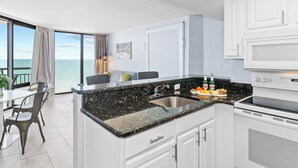 A modern kitchen with a large island, white cabinets, and a view of the ocean. - Remodeled Dec23/Best Floorpan/DogsOK (Myrtle Beach)