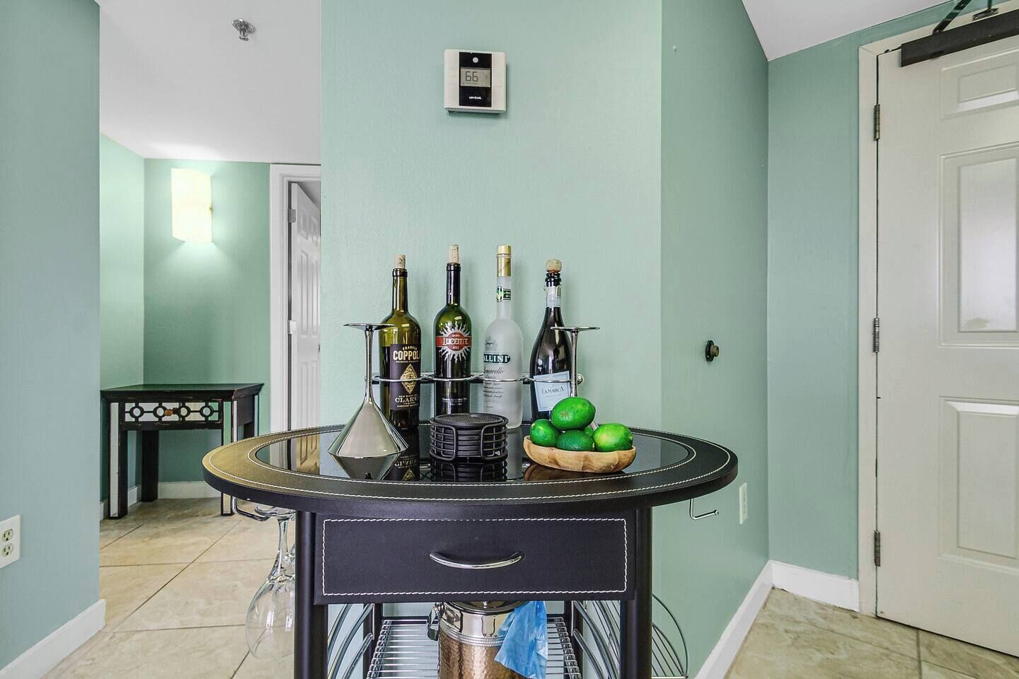 A dining area with a round table displaying bottles and a bowl of limes.