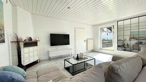 A modern living room with a large TV, a glass coffee table, and a sofa. - Townhouse Lotus in a prime location! 5 minutes from Legoland. families & pets. (Günzburg)