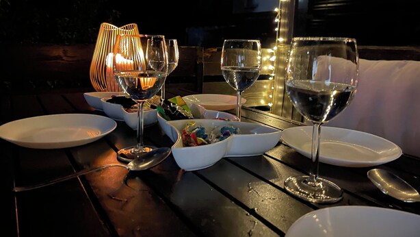 A dining table set with white plates, bowls, and wine glasses, accompanied by a candle and string lights. - Townhouse Lotus in a prime location! 5 minutes from Legoland. families & pets. (Günzburg)