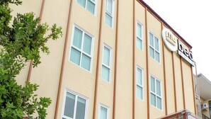 A multi-story hotel with a beige facade, a 'mybed Gold' sign, and a modern entrance with a wooden fence. - My Bed Gold Hotel (Chonburi)