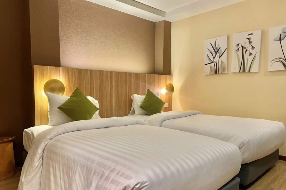 A hotel room with two beds, wooden headboard, and wall-mounted artwork.