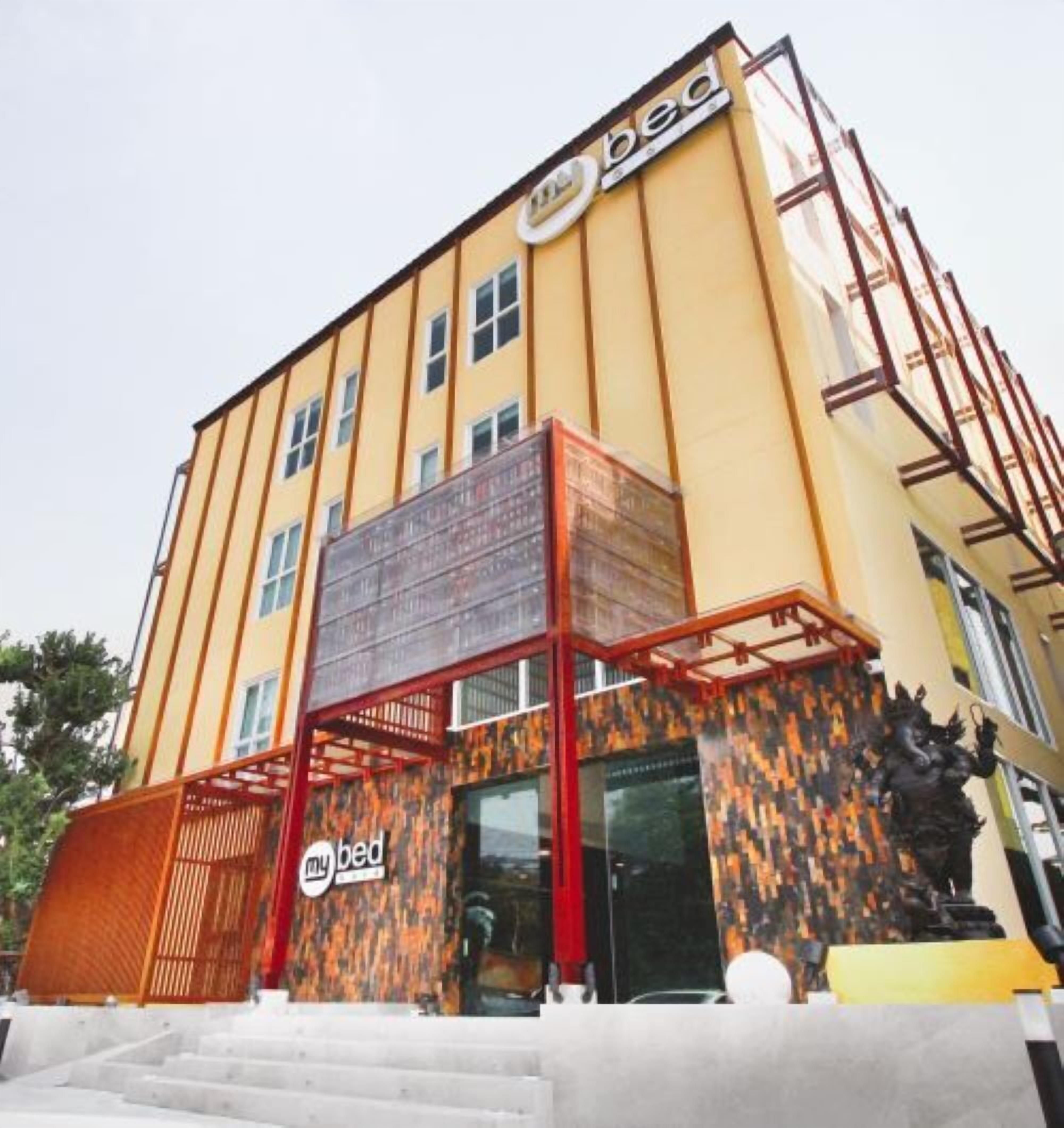 A building with a yellow facade, a sign reading "bed," and a staircase leading to the entrance.