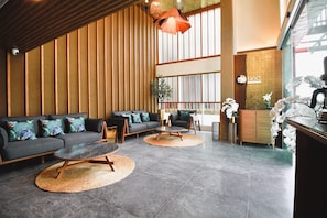 A modern lobby with a sofa, chairs, a coffee station, and a reception desk. - My Bed Gold Hotel (Chonburi)