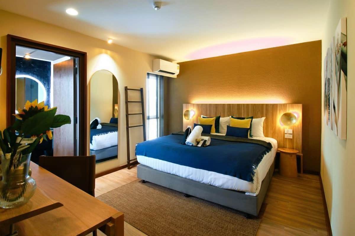 A modern bedroom with a large bed, bedside lamps, a mirror, and a wooden floor.