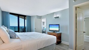 Une chambre d’hôtel avec un lit, une télévision, une porte et une vue sur l’océan.