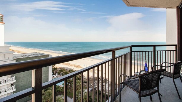 Un balcon avec vue sur la plage et l’océan.
