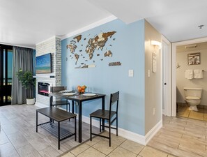 A dining area with a world map mural, a potted plant, and a table set for two. - Inviting 1BR Oceanview Suite/Dogs OK (Myrtle Beach)