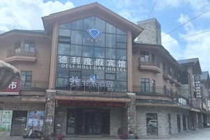 Un hotel con un letrero llamativo, un balcón y una tienda en la planta baja.