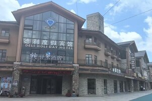 Un hotel con un cartel llamativo que dice 'DELI HOLIDAY HOTEL' y un logotipo sobre la entrada.