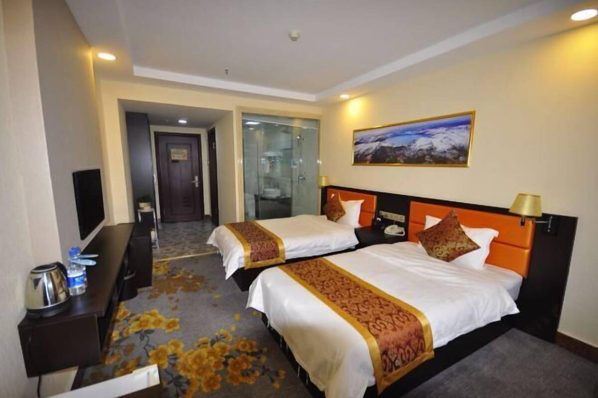 A hotel room with two beds, a television, a desk, and a painting on the wall.