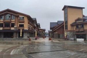 Un edificio con varios pisos y balcones, un patio con una fuente y suelo h úmedo que sugiere lluvia reciente.