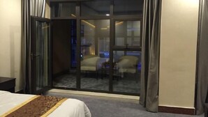 Una habitación de hotel con una cama, un ventanal corredero a un balcón y una pequeña mesa.