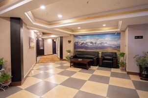 Un vestíbulo de hotel con piso a cuadros, un sofá y una pintura de montañas.