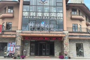 Un hotel con un letrero grande que dice 'DELI HOLIDAY HOTEL' y un letrero más pequeño debajo.