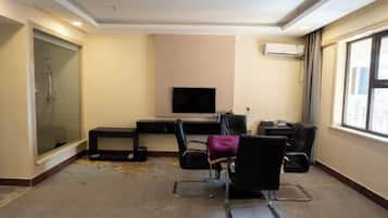 Habitación de hotel con cama, escritorio, silla, televisor y ventana.