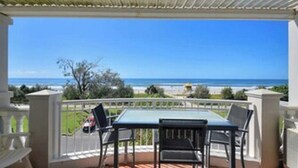 Ein Balkon mit Tisch und Stühlen, mit Blick auf Strand und Meer.