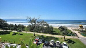 Ein Küstenblick mit Parkplatz, Strand und einem gelben Gebäude.