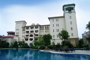 Un grand bâtiment doté de nombreux balcons et d’un espace piscine.