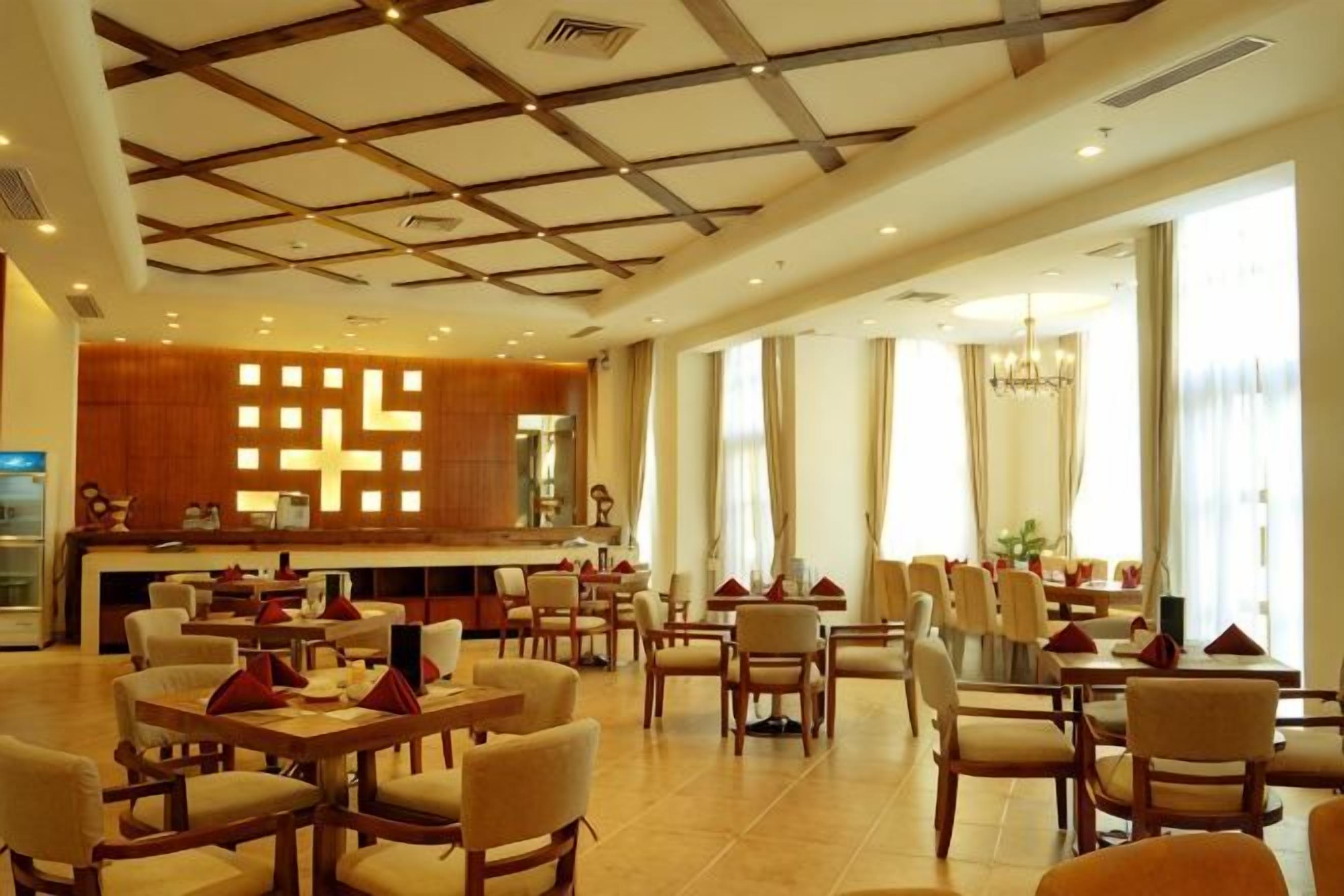 Un hall de hotel con varias zonas de estar, un mostrador de recepción y amplios ventanales.