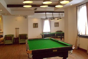 Una mesa de billar en una habitación con sillas y un soporte para bolas.