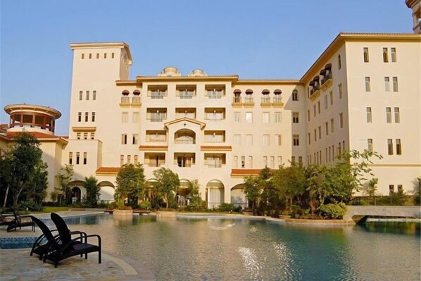 Un hôtel doté d’une piscine, de plusieurs balcons et d’une cour intérieure agrémentée de palmiers.