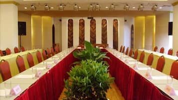 A conference room with a long table, chairs, and a potted plant.