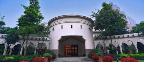 A building with a circular entrance, arched walkways, and potted plants.