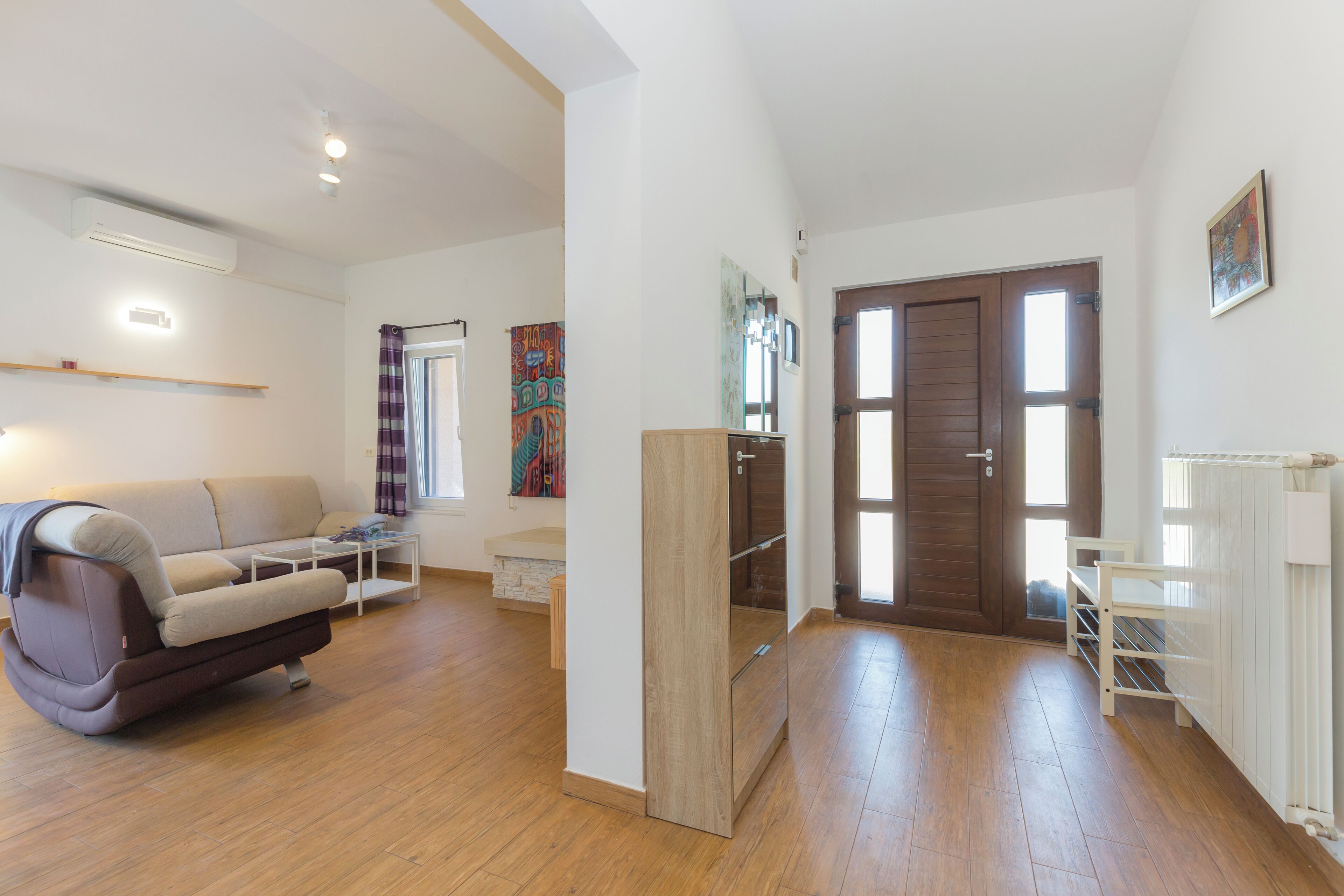 A spacious living room with a sofa, a coffee table, and a wooden floor.
